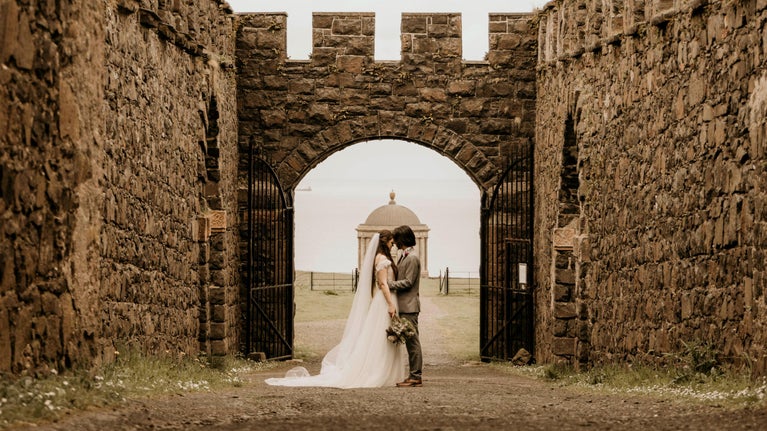 An image of a bride and groom standing in the ruins of Downhill House.